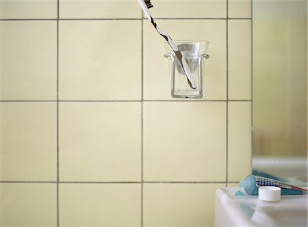 simsearch:696-03395895,k - Toothbrush in cup holder on wall next to bathroom sink Stock Photo - Premium Royalty-Free, Code: 632-01149511