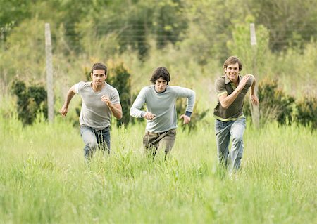 friends competing - Three young male friends racing across field Stock Photo - Premium Royalty-Free, Code: 632-01154535