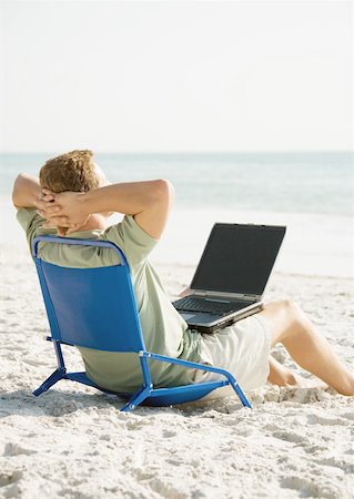 Man sitting on beach with computer on lap Stock Photo - Premium Royalty-Free, Code: 632-01154719