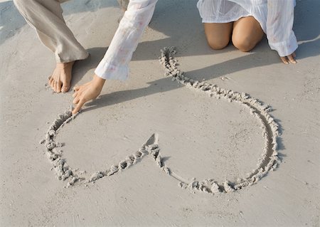 romantic couples anonymous - Woman drawing heart in sand on beach, partial view Stock Photo - Premium Royalty-Free, Code: 632-01156241