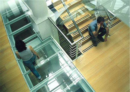 simsearch:700-06038236,k - Woman walking past man sitting on stairs talking on cell phone, view from above Stock Photo - Premium Royalty-Free, Code: 632-01150007