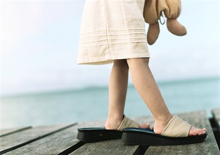 Girl wearing woman's shoes, low section, sea in background Stock Photo - Premium Royalty-Free, Code: 632-01150373