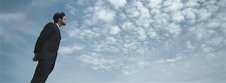 Man in suit standing with sky in background, low angle view Stock Photo - Premium Royalty-Free, Code: 632-01151400