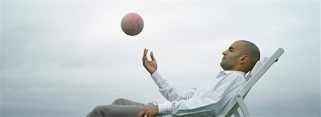 simsearch:632-01161489,k - Man sitting outdoors in lounge chair throwing ball into air, side view Foto de stock - Sin royalties Premium, Código: 632-01151411