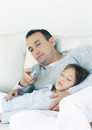 Man sitting on couch pointing remote control, holding sleeping daughter on lap Stock Photo - Premium Royalty-Free, Code: 632-01151540