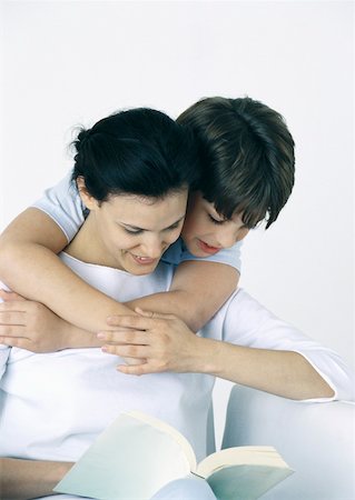 simsearch:632-03027302,k - Woman and son reading book, boy with arms around woman, looking over her shoulder Stock Photo - Premium Royalty-Free, Code: 632-01151557