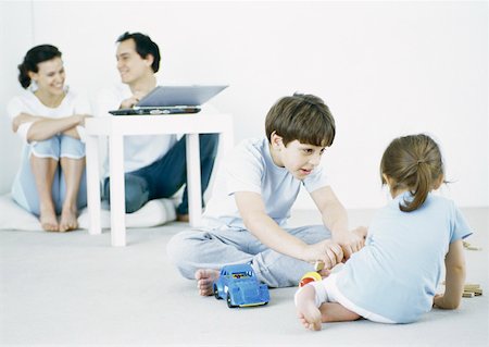simsearch:649-06812444,k - Boy and girl playing on floor, parents using laptop in background Foto de stock - Sin royalties Premium, Código: 632-01151558