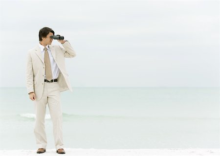 Businessman using binoculars, standing on beach Stock Photo - Premium Royalty-Free, Code: 632-01160288