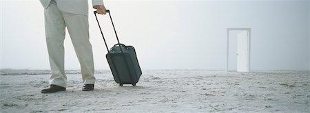 Businessman with suitcase on beach, doorway in background Stock Photo - Premium Royalty-Free, Code: 632-01160695