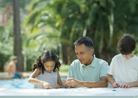 pool kids - Mature man putting together puzzle with grandchildren Foto de stock - Sin royalties Premium, Código: 632-01194015