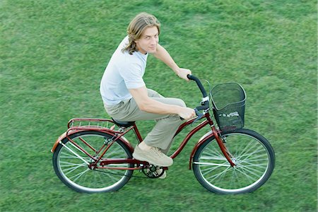 riding bike with basket - Young man riding bicycle on grass, high angle view Stock Photo - Premium Royalty-Free, Code: 632-01276720