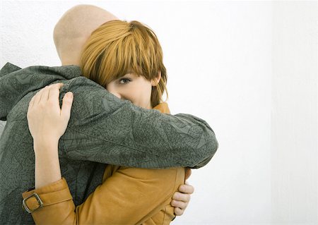 Young man and woman hugging, woman looking over man's arm, looking at camera Stock Photo - Premium Royalty-Free, Code: 632-01270527