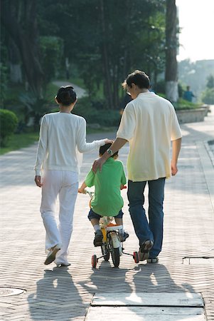 simsearch:400-06412547,k - Parents walking next to son on bicycle with training wheels, rear view Stock Photo - Premium Royalty-Free, Code: 632-01270654