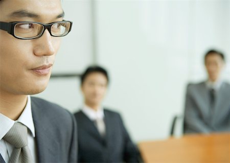 simsearch:632-03403433,k - Businessman glancing away, colleagues sitting in blurred background Stock Photo - Premium Royalty-Free, Code: 632-01271879