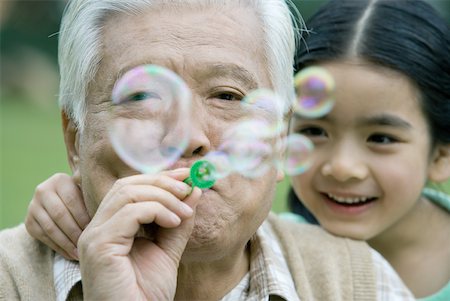 simsearch:632-05604245,k - Senior man blowing bubbles, girl leaning on shoulder, close-up Stock Photo - Premium Royalty-Free, Code: 632-01271982