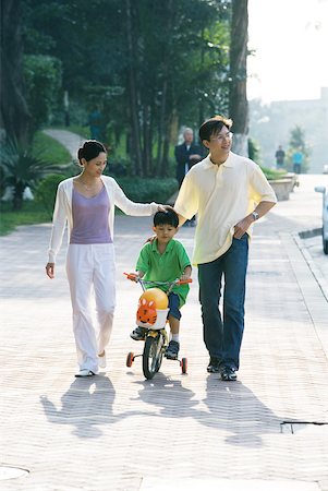 simsearch:400-06412547,k - Boy riding bicycle with training wheels, parents on either side, front view Stock Photo - Premium Royalty-Free, Code: 632-01272008