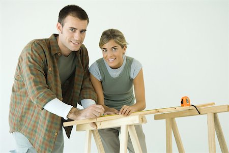 Couple leaning on sawhorses, using measuring tape, smiling at camera Stock Photo - Premium Royalty-Free, Code: 632-01380541