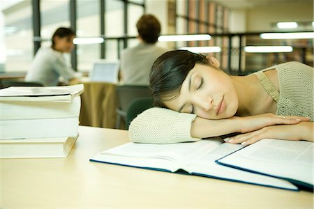 Young woman in university library, head on arm, asleep Stock Photo - Premium Royalty-Free, Code: 632-01611726