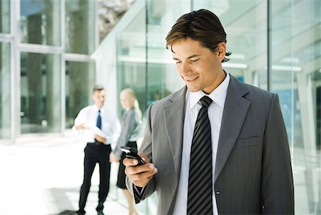 simsearch:695-03376228,k - Young businessman looking at cell phone, smiling, portrait Stock Photo - Premium Royalty-Free, Code: 632-01612077