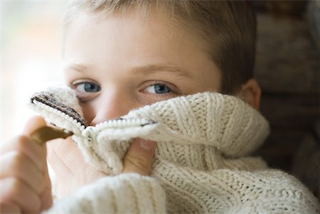 simsearch:695-03376367,k - Boy zipping collar of wool sweater over face, close-up Stock Photo - Premium Royalty-Free, Code: 632-01613104