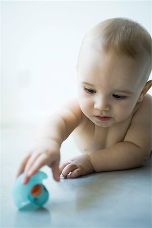 simsearch:632-03027302,k - Baby lying on floor, reaching for rubber duck Stock Photo - Premium Royalty-Free, Code: 632-01636943