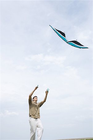 sky in kite alone pic - Man flying kite, low angle view Foto de stock - Sin royalties Premium, Código: 632-01638828