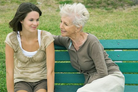 Grandmother and teenage granddaughter sitting together on bench, both smiling Stock Photo - Premium Royalty-Free, Code: 632-01784326
