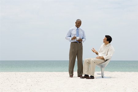 simsearch:632-03500607,k - Two business associates chatting on beach, one holding coffee cup Stock Photo - Premium Royalty-Free, Code: 632-01785097