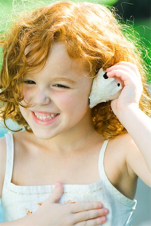 simsearch:632-01193783,k - Little girl holding seashell up to ear, smiling, looking away Stock Photo - Premium Royalty-Free, Code: 632-02007461