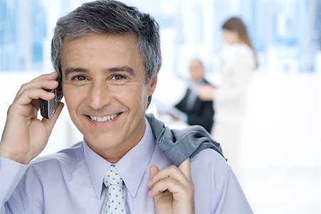 simsearch:695-03376228,k - Mature businessman using cell phone in office, holding jacket over shoulder, smiling at camera Stock Photo - Premium Royalty-Free, Code: 632-02008156