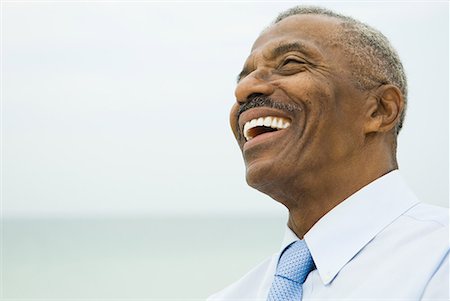 Senior businessman laughing, sea in background, head and shoulders Stock Photo - Premium Royalty-Free, Code: 632-02038800