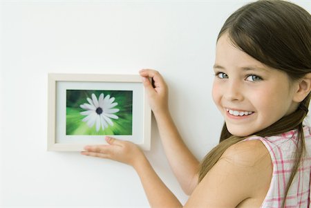 silhouette of human hanging - Little girl holding framed picture against wall, smiling over shoulder at camera Stock Photo - Premium Royalty-Free, Code: 632-02227812