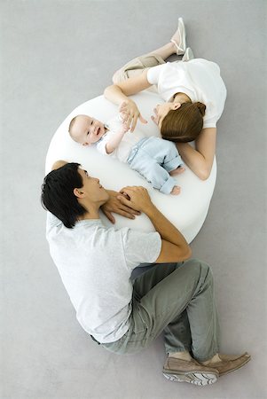 simsearch:632-03027302,k - Parents and baby relaxing on ottoman, baby holding mother's hand, overhead view Stock Photo - Premium Royalty-Free, Code: 632-02282496