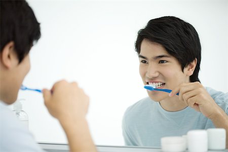 simsearch:696-03395895,k - Young man brushing teeth, looking at self in mirror Stock Photo - Premium Royalty-Free, Code: 632-02282589