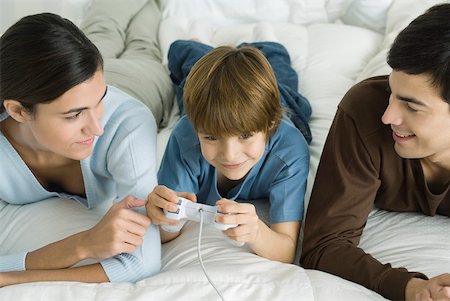 simsearch:632-03424261,k - Family lying together on bed, boy playing video game Stock Photo - Premium Royalty-Free, Code: 632-02282905