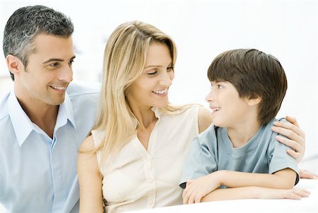 simsearch:632-05816381,k - Family sitting together, smiling, mother's arm around son's shoulder Stock Photo - Premium Royalty-Free, Code: 632-02282988