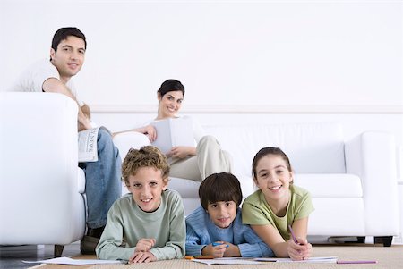 simsearch:695-05769087,k - Family relaxing in living room, children coloring on the floor, parents sitting on sofa Stock Photo - Premium Royalty-Free, Code: 632-02345158