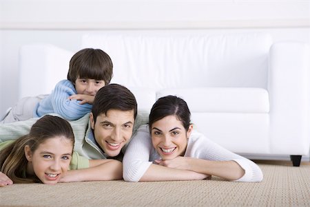 simsearch:695-05769087,k - Family lying together on floor, son lying on his father's back, all smiling at camera Stock Photo - Premium Royalty-Free, Code: 632-02345161