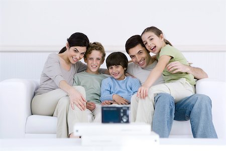 Family sitting together on sofa, posing for digital camera set in foreground Stock Photo - Premium Royalty-Free, Code: 632-02345171