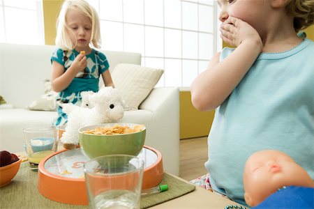 simsearch:695-03380694,k - Little girl looking at bowl of cereal with hand over mouth, sister in background Stock Photo - Premium Royalty-Free, Code: 632-02645164