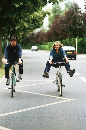 pedal - Couple riding bikes, woman doing trick Stock Photo - Premium Royalty-Free, Code: 632-02744794