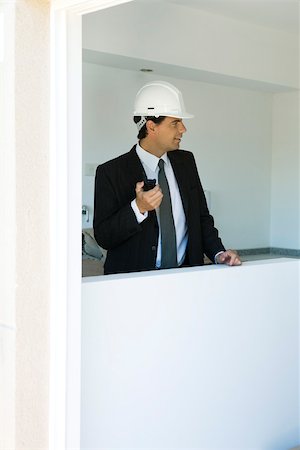 simsearch:632-03403433,k - Man in suit wearing hard hat holding walkie-talkie looking out window Stock Photo - Premium Royalty-Free, Code: 632-02885283