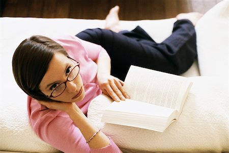 simsearch:632-03083700,k - Woman sitting on sofa reading book, looking up at camera, high angle view Stock Photo - Premium Royalty-Free, Code: 632-03027052