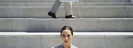 simsearch:632-05401320,k - Businesswoman on steps, looking at camera, man walking in background Stock Photo - Premium Royalty-Free, Code: 632-03083030