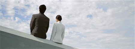 simsearch:632-03083042,k - Businessman and businesswoman sitting side by side on rooftop ledge Stock Photo - Premium Royalty-Free, Code: 632-03083050