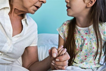 Grandmother and young granddaughter holding hands and talking, cropped Stock Photo - Premium Royalty-Free, Code: 632-03083186