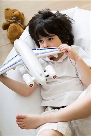 simsearch:632-03424261,k - Little boy lying on beanbag chair, playing with toy airplane Stock Photo - Premium Royalty-Free, Code: 632-03083570