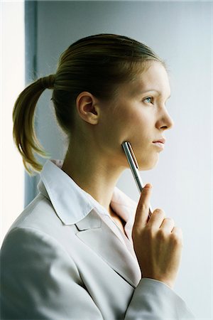 simsearch:632-03083042,k - Young businesswoman looking away in thought, holding pen up to face Stock Photo - Premium Royalty-Free, Code: 632-03083758