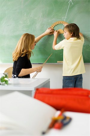 Teacher showing elementary student how to draw angle using protractor Stock Photo - Premium Royalty-Free, Code: 632-03193646