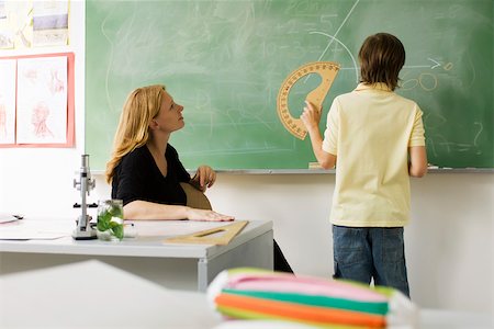 Boy standing in front of classroom blackboard, using protractor Stock Photo - Premium Royalty-Free, Code: 632-03193649